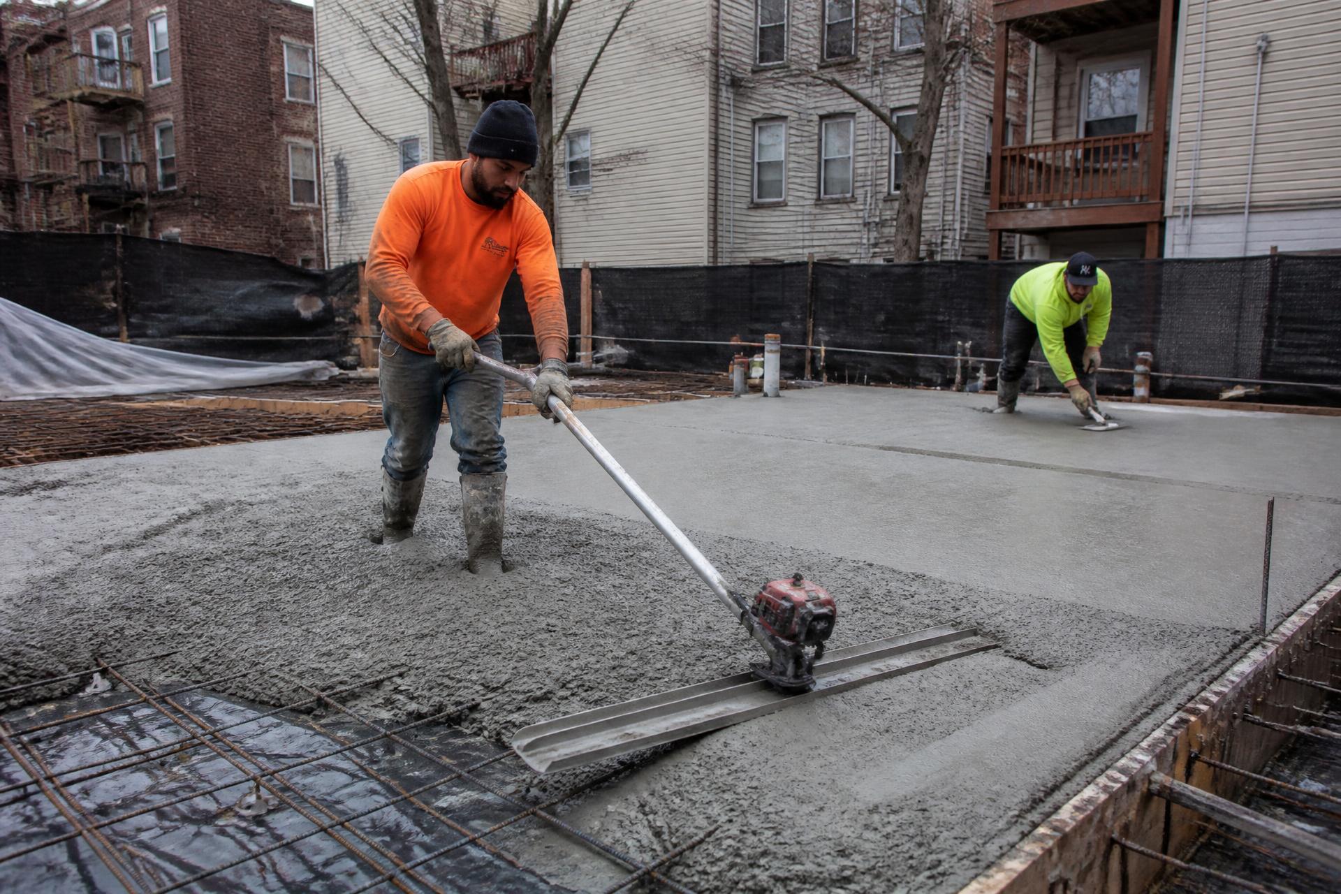 Concrete crew screeding and floating a freshly poured slab on a New York job site